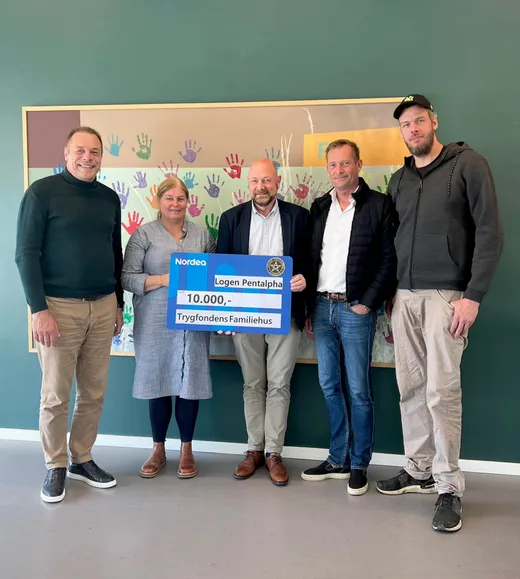 Fem personer holder en stor check på 10.000 kr. fra Logen Pentalpha til Trygfondens Familiehus