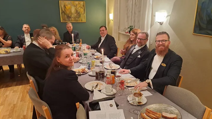 Brødre og ledsagere smiler til kameraet ved et festligt middagsbord med levende lys