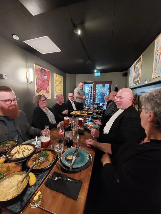 Brødre og ledsagere samlet om et langt bord med mad på en restaurant